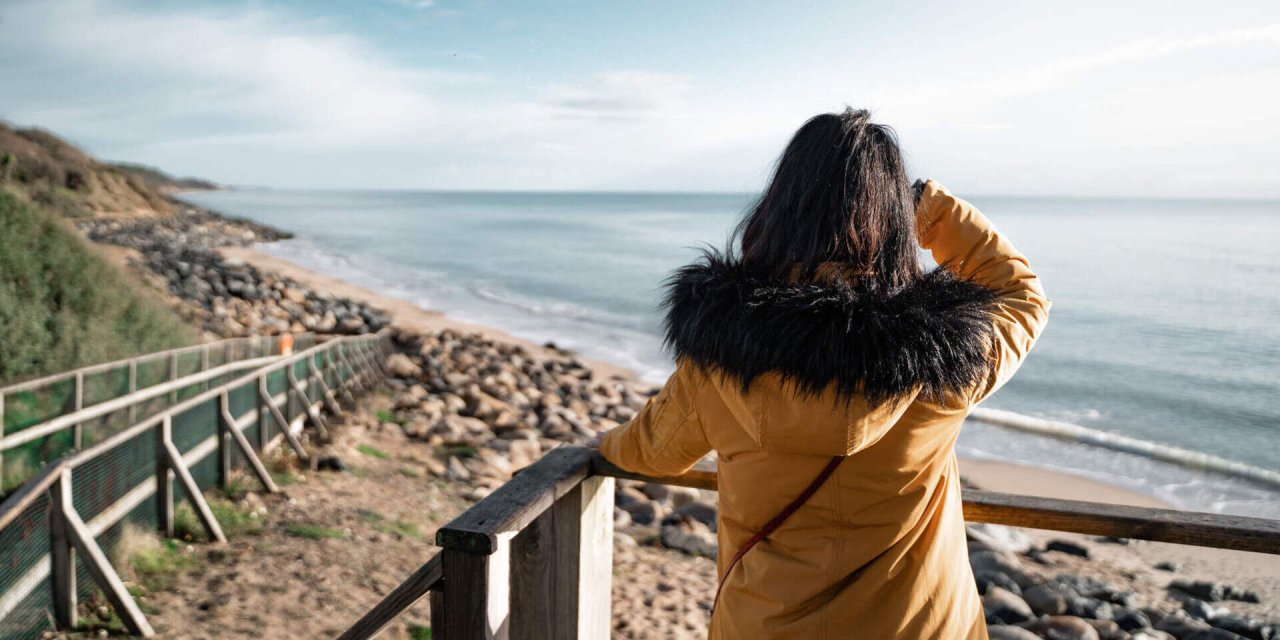 woman in yellow jacket looking out over water 